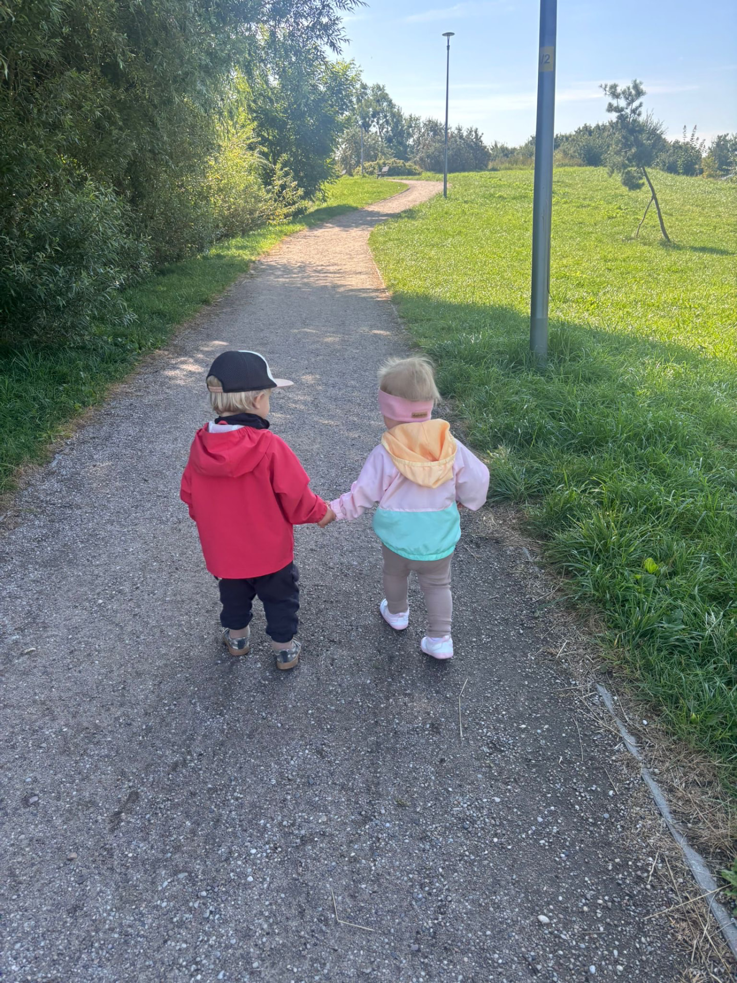 Dwoje dzieci idzie za ręce ścieżką w parku